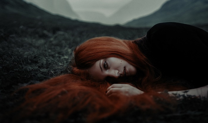Woman with red hair lying down in nature