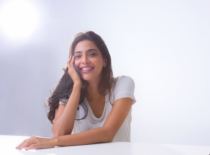 Aishwarya Lekshmi smiling, sitting at a table