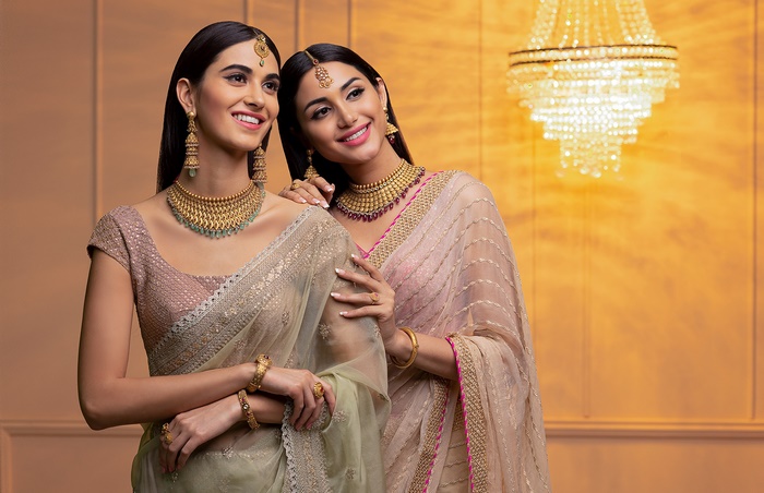 Two Indian women wearing traditional jewelry and sarees