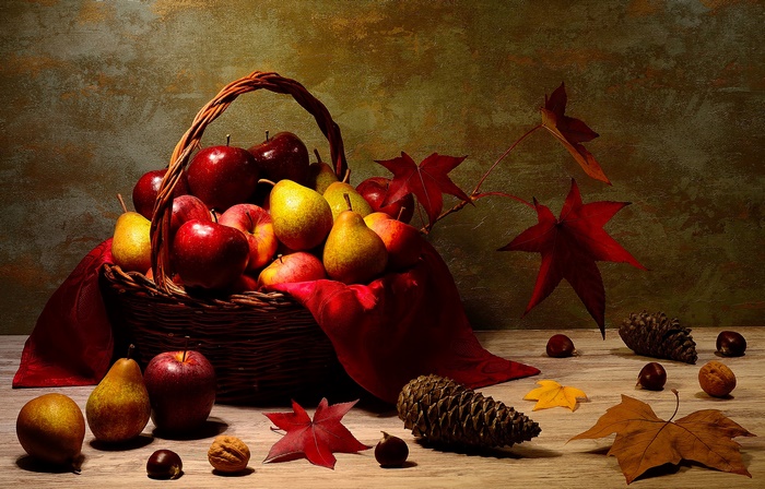 Still life of apples and pears in a basket with autumn leaves