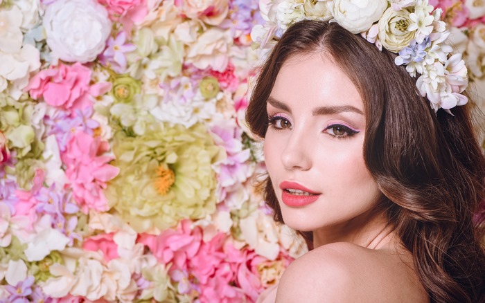 Model with floral wreath against flower wall