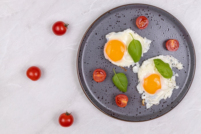 Fried eggs with cherry tomatoes and basil on a plate