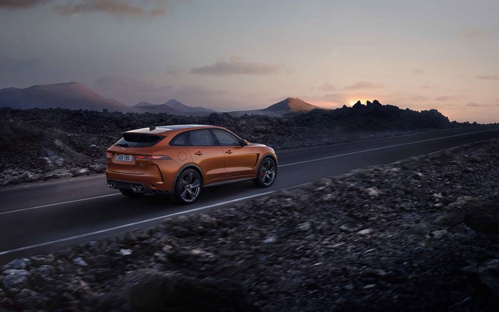 Orange Jaguar F-Pace SVR driving on a road at sunset