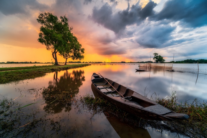 Boat on a river during sunset with clouds