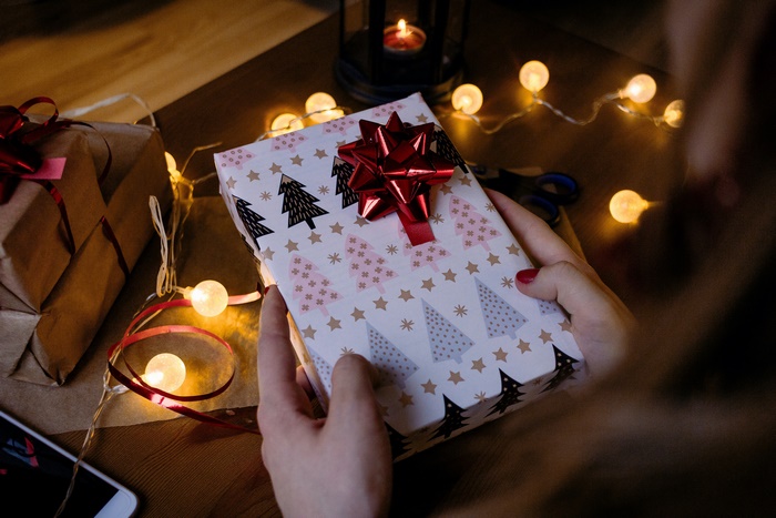 Hands wrapping a Christmas gift with fairy lights
