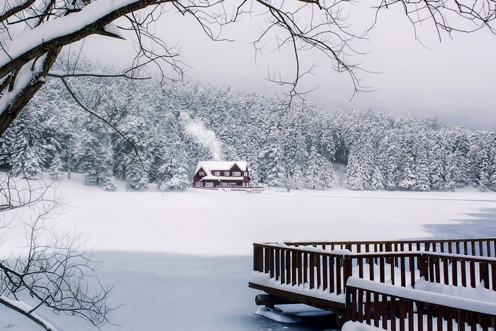 Red house by snowy lake and forest in Turkey