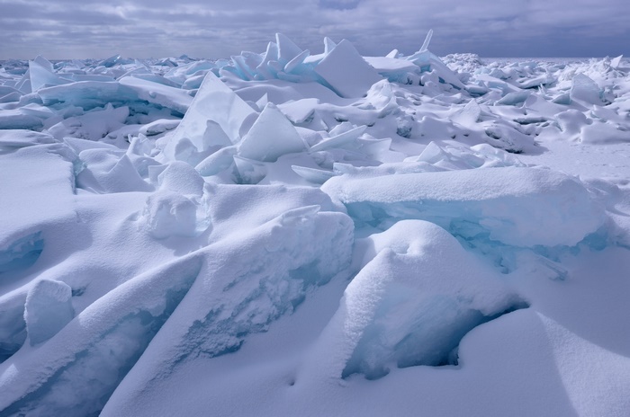 Broken ice floes covered in snow under a cloudy sky
