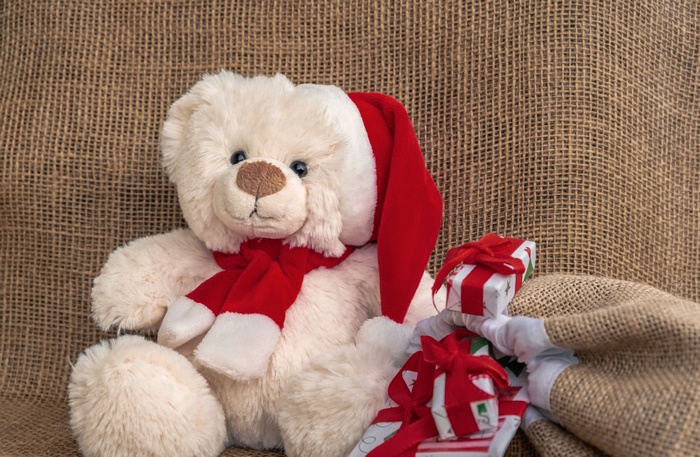 Teddy bear with Santa hat and gifts on burlap
