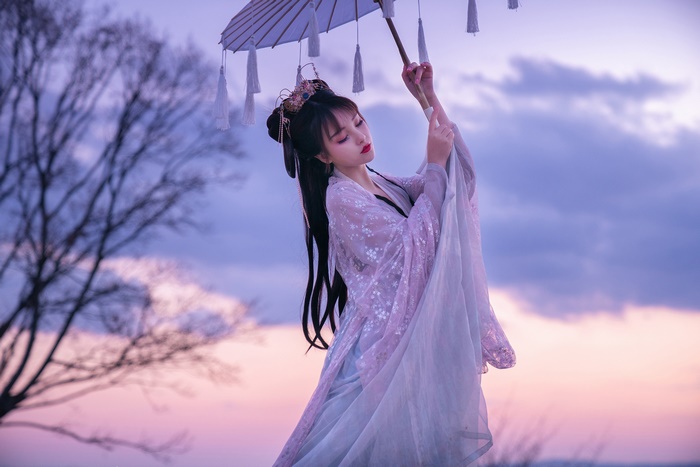 Elegant Asian Woman with Umbrella at Sunset