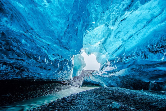 Inside a blue ice cave with a stream