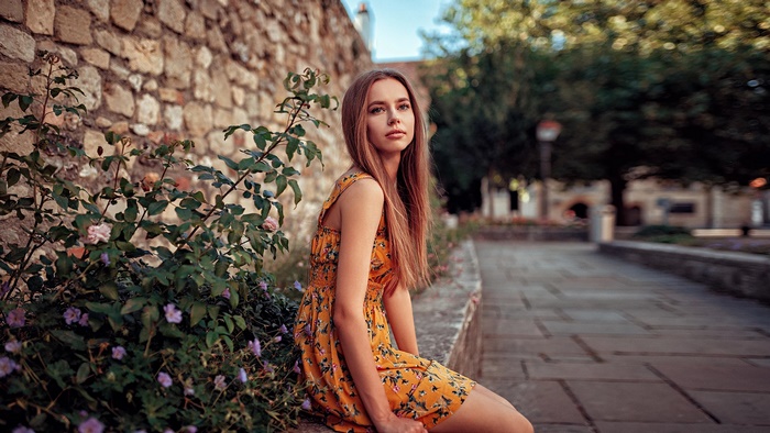 Woman in yellow floral dress sitting outdoors
