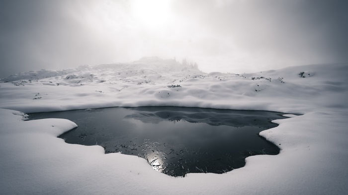 Winter landscape with frozen pond and fog