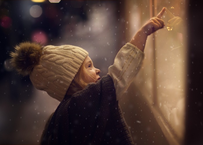 Girl in winter hat pointing at window