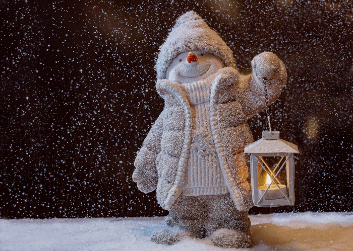 Snowman holding a lantern in snowfall