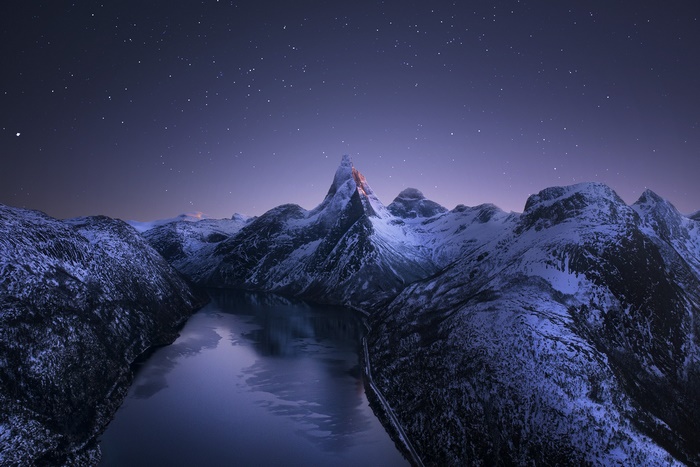 Snowy mountains and lake under a starry night sky