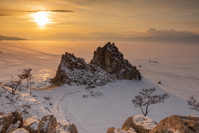Winter sunset over frozen lake with rock formation