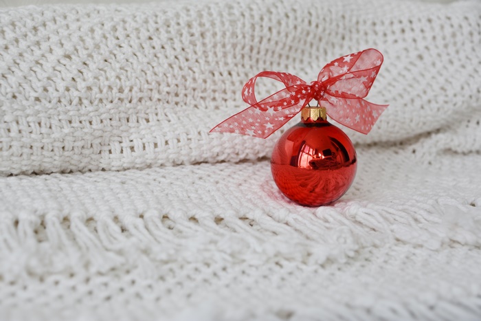 Red Christmas Ornament with Red Bow on White Blanket