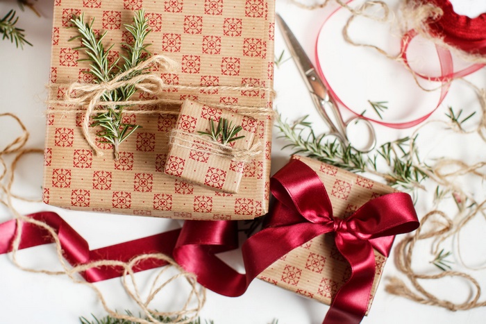 Christmas gifts wrapped with red patterned paper and rosemary sprigs