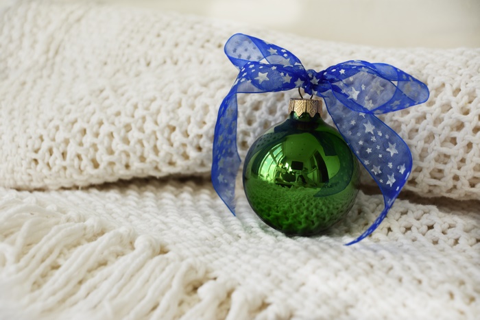 Green Christmas Ornament with Blue Ribbon on White Blanket 4K