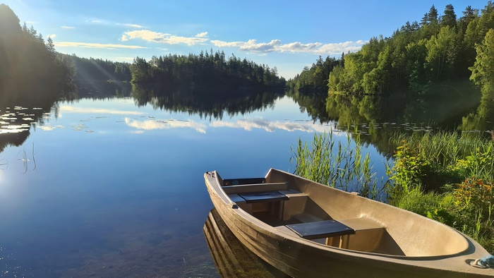 Boat on a calm lake with forest reflection