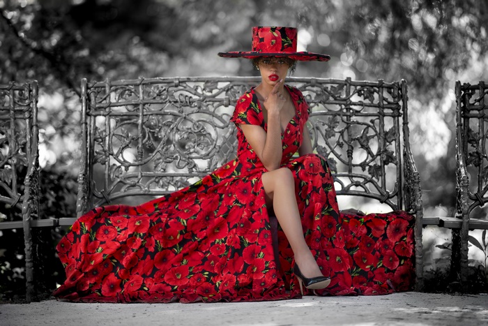Woman in poppy dress and hat on bench