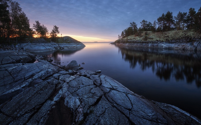 Rocky shore of a calm lake at dusk