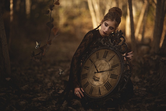 Woman with antique clock and butterflies in forest