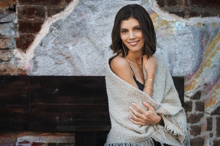 Woman with dark hair smiling, wrapped in a shawl