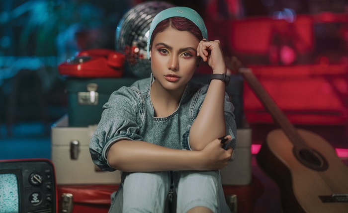 Woman with bandana and denim outfit sitting with luggage