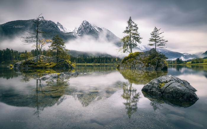Lake with rocks and mountains in fog