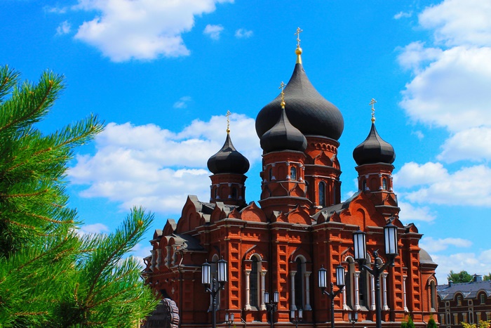 Red brick church with black domes under blue sky