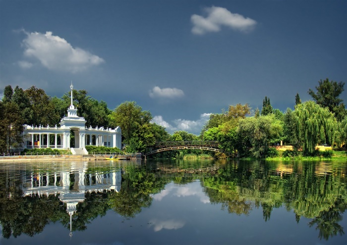 White building with columns on a river with reflections