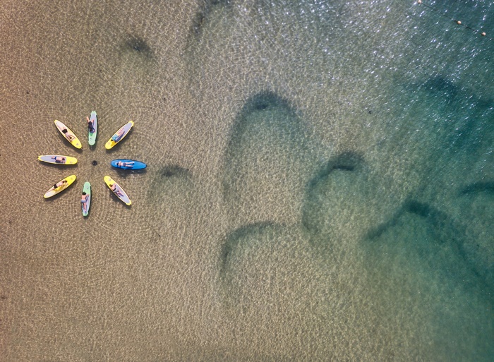 People on paddleboards arranged in a circle on shallow water