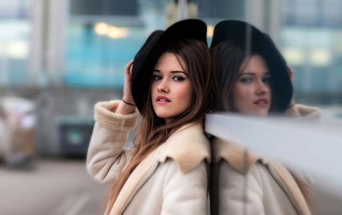Woman in hat and coat reflected in glass