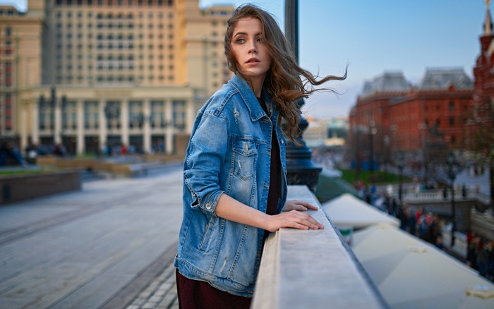 Woman in denim jacket leaning on a railing