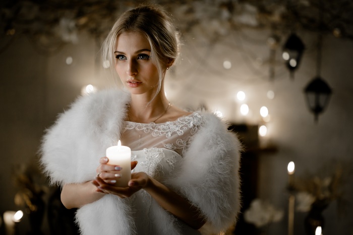 Blonde woman in white dress holding a candle