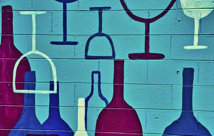 Graffiti of wine bottles and glasses on a brick wall