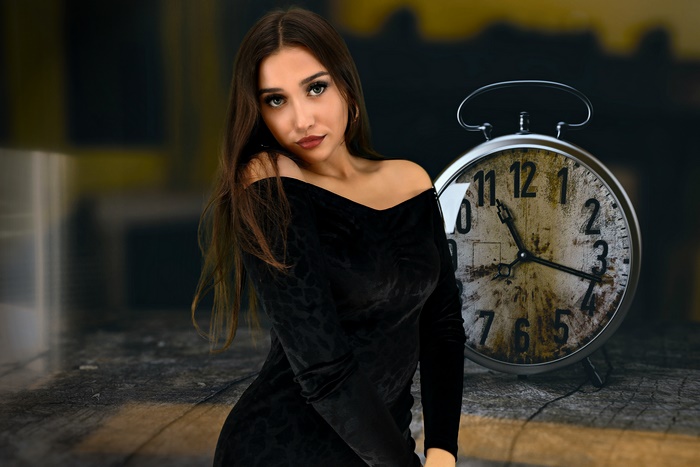 Brunette woman in black dress with alarm clock