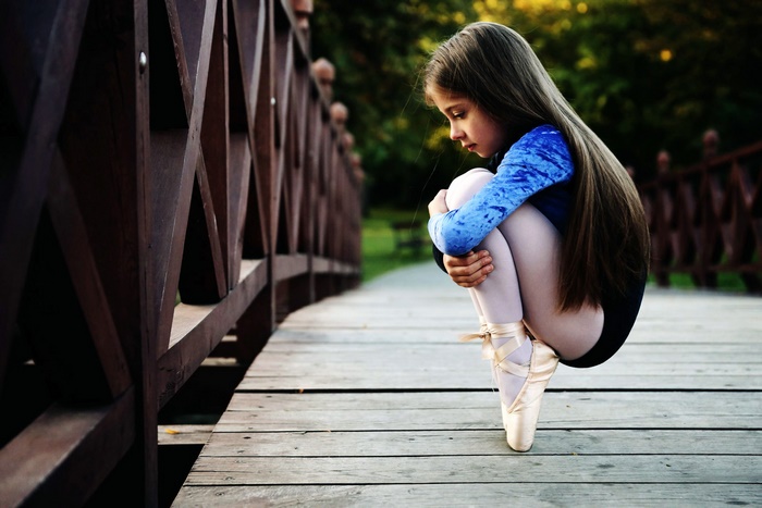 Ballerina sitting on a wooden bridge