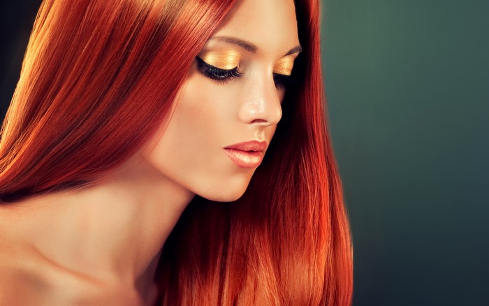 Woman with long red hair and gold makeup