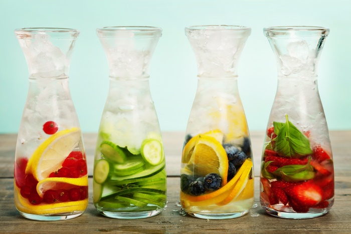 Four carafes of infused water with fruits and ice