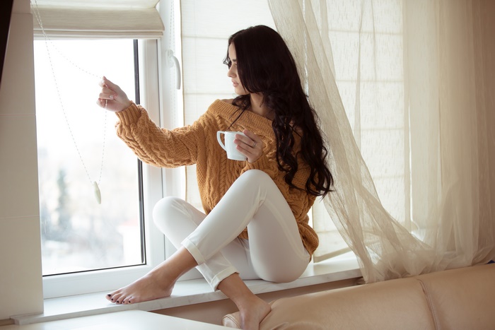 Woman in sweater by window with coffee