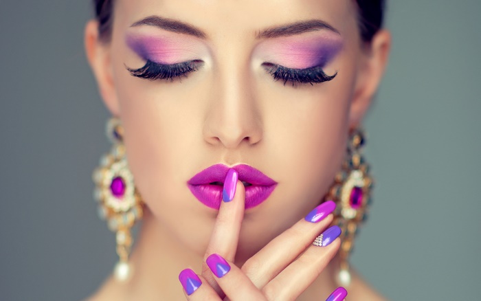 Model with purple makeup and large earrings