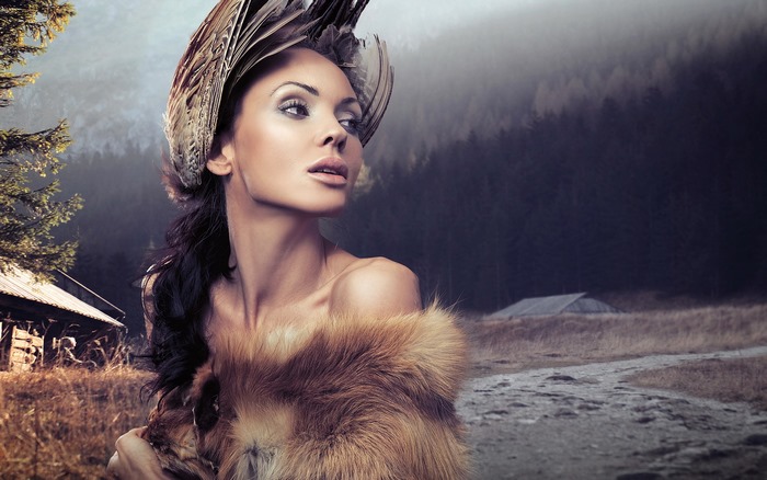 Woman with feather headdress and fur in a forest