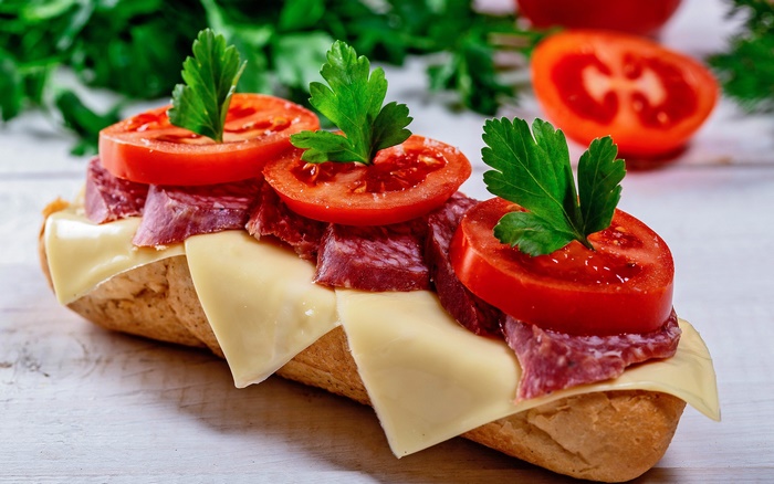 Sandwich with salami, cheese, tomato, and parsley