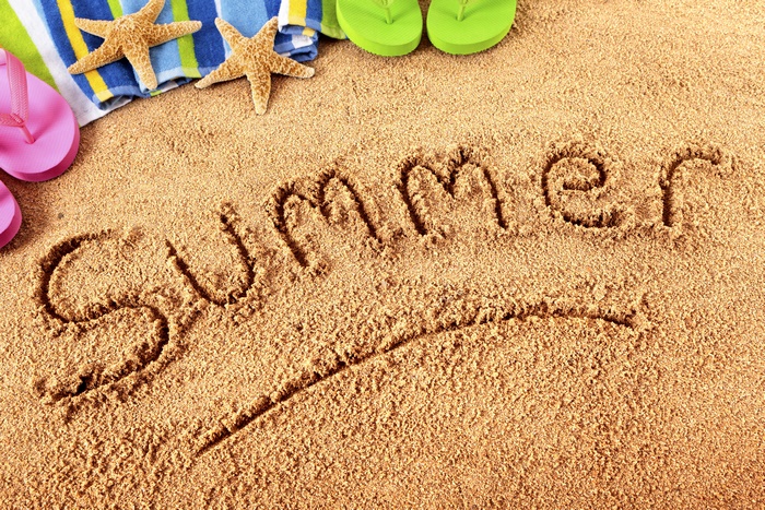 Summer written in sand with beach accessories
