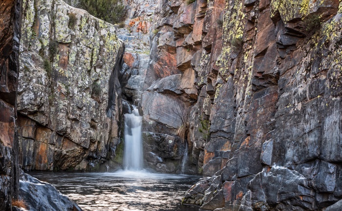 Waterfall cascading into a pool surrounded by rocky cliffs