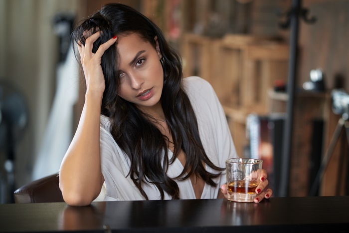 Woman with black hair and brown eyes holding a drink