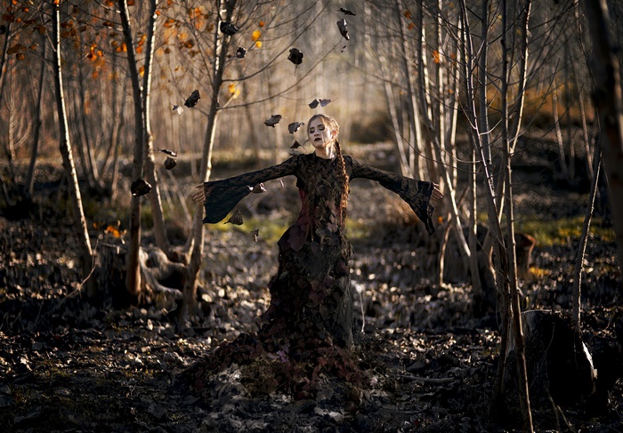 Woman in leaf dress with braid in autumn forest