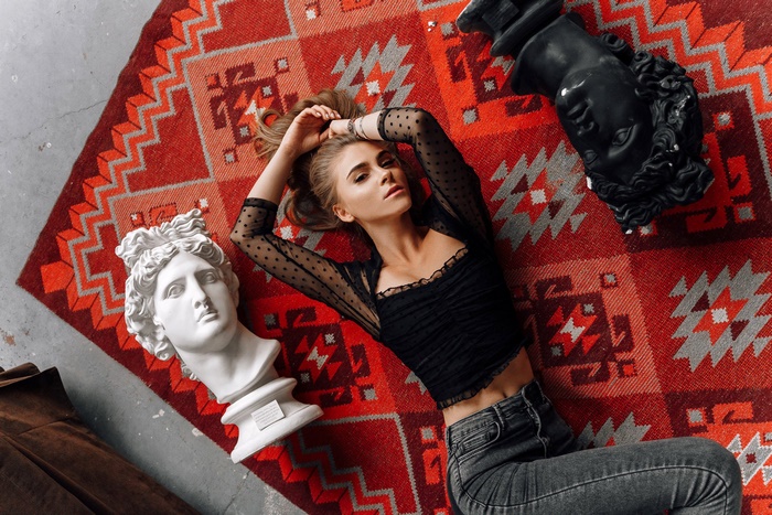 Woman lying on a rug with sculptures